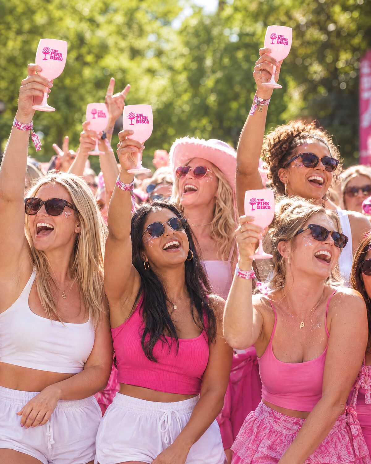 Women in pink outfits and cowboy hats dancing in the sun